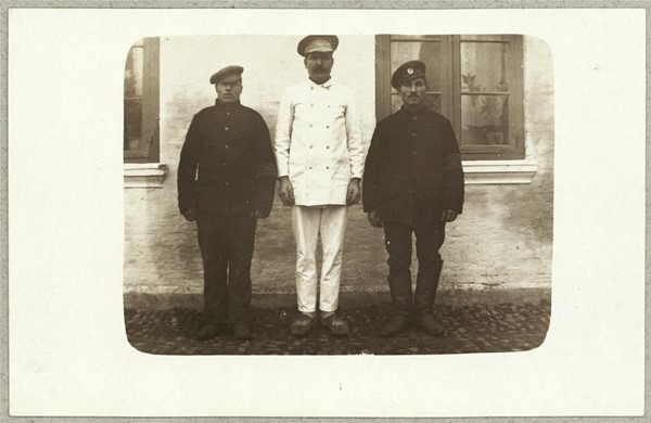 Tre russiske krigsfanger foran hus