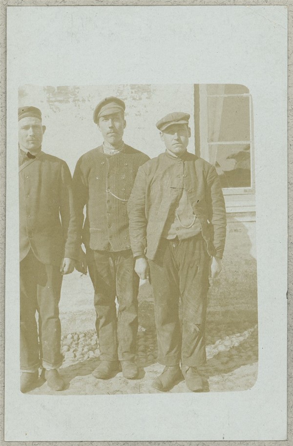 Tre russiske krigsfanger foran hus