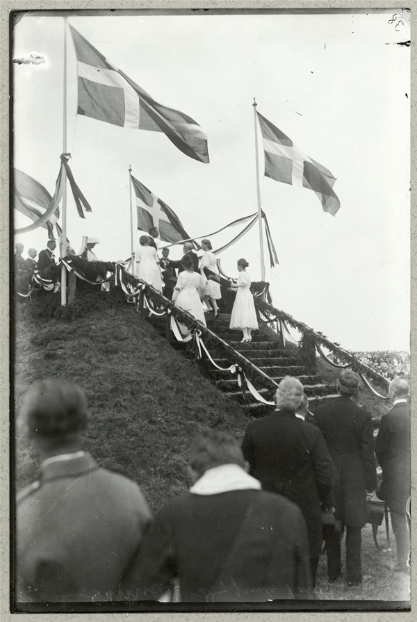 Sønderjyske piger overrækker Kong Chistian X et gammelt Dannebrog ved genforeningsfesten d. 11. juli 1920 i Dybbøl Skanser